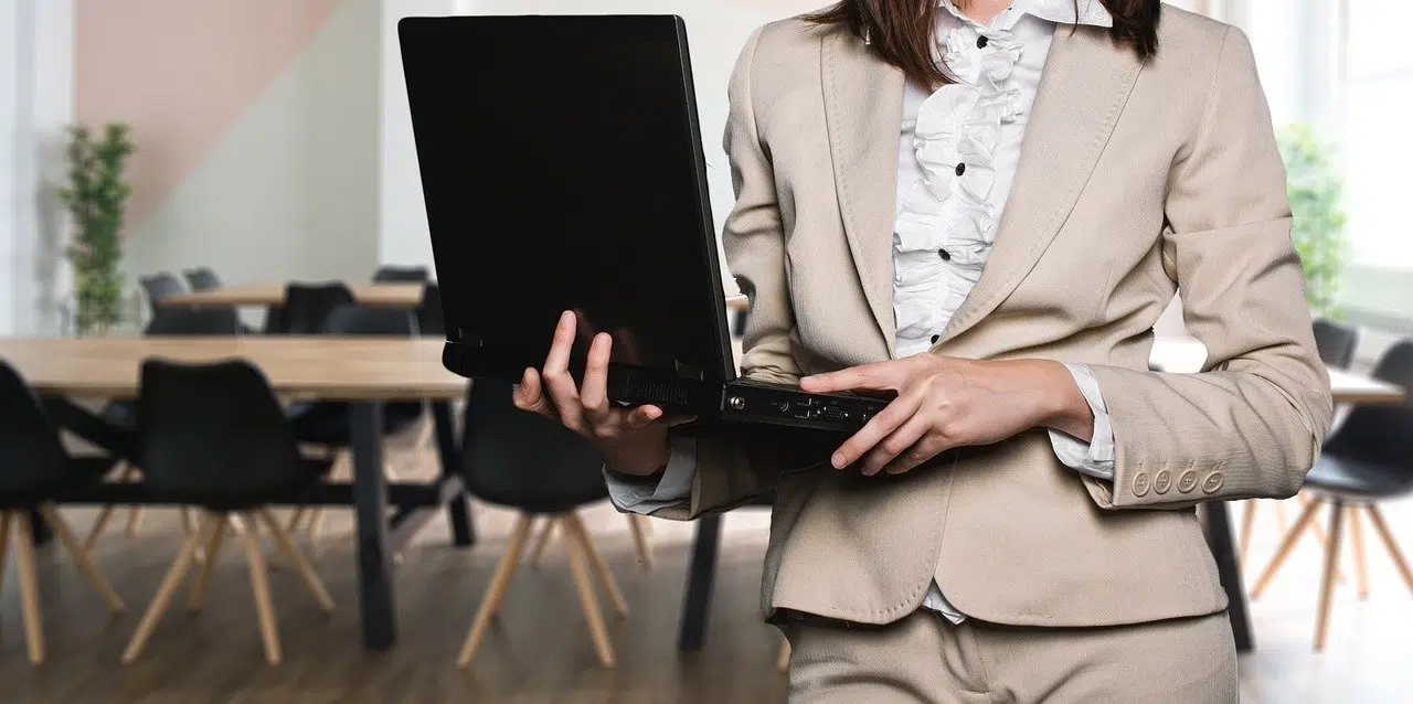 Une femme debout avec un ordinateur dans les mains